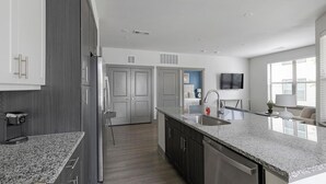 A modern kitchen with granite countertops, stainless steel appliances, and dark cabinetry.