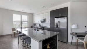 Una cocina moderna con una isla grande, electrodomésticos de acero inoxidable y una zona de comedor con taburetes de bar.