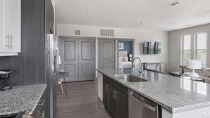 Una cocina moderna con encimeras de granito, electrodomésticos de acero inoxidable y una isla central.