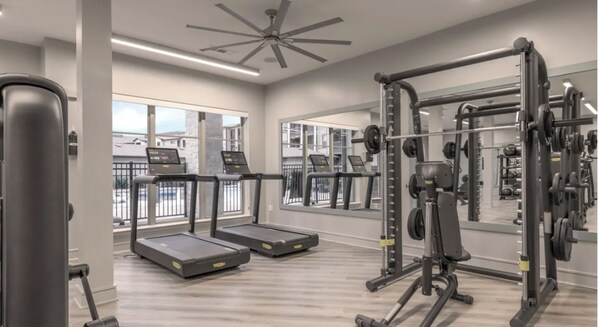 A modern gym with treadmills, weight machines, and a large mirror.