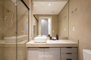 Une salle de bain moderne dotée d’une douche à parois de verre, d’un lavabo central et d’un meuble-lavabo avec des tiroirs.