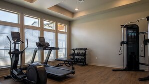 A home gym with a treadmill, elliptical, dumbbells, and a weight machine. - Landing | Modern 3BD, Gym, Pool (Waller)
