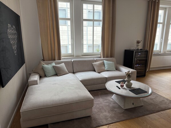 A modern living room with a sectional sofa, a glass coffee table, and a blackboard on the wall.