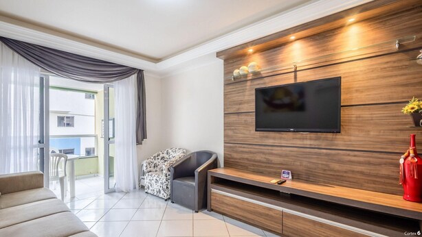 Un salon moderne avec un téléviseur à écran plat fixé à un mur en bois, un canapé, une table basse et un balcon avec vue.