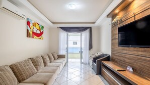 Un salon moderne avec un canapé beige, un téléviseur à écran plat et un meuble de rangement en bois.