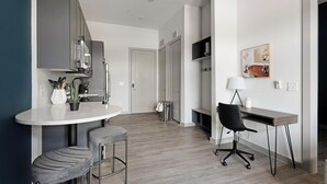 Een moderne keuken met een ronde eettafel, twee barkrukken en een zwarte bureaustoel.