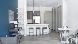 Una cocina moderna con una isla central, taburetes de bar y una mesa de comedor con sillas.