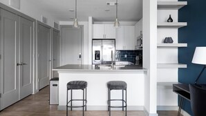 A modern kitchen with a central island, bar stools, pendant lighting, and a built-in oven. - Landing | Spectacular 1BD, Game Room, Gym (Austin)