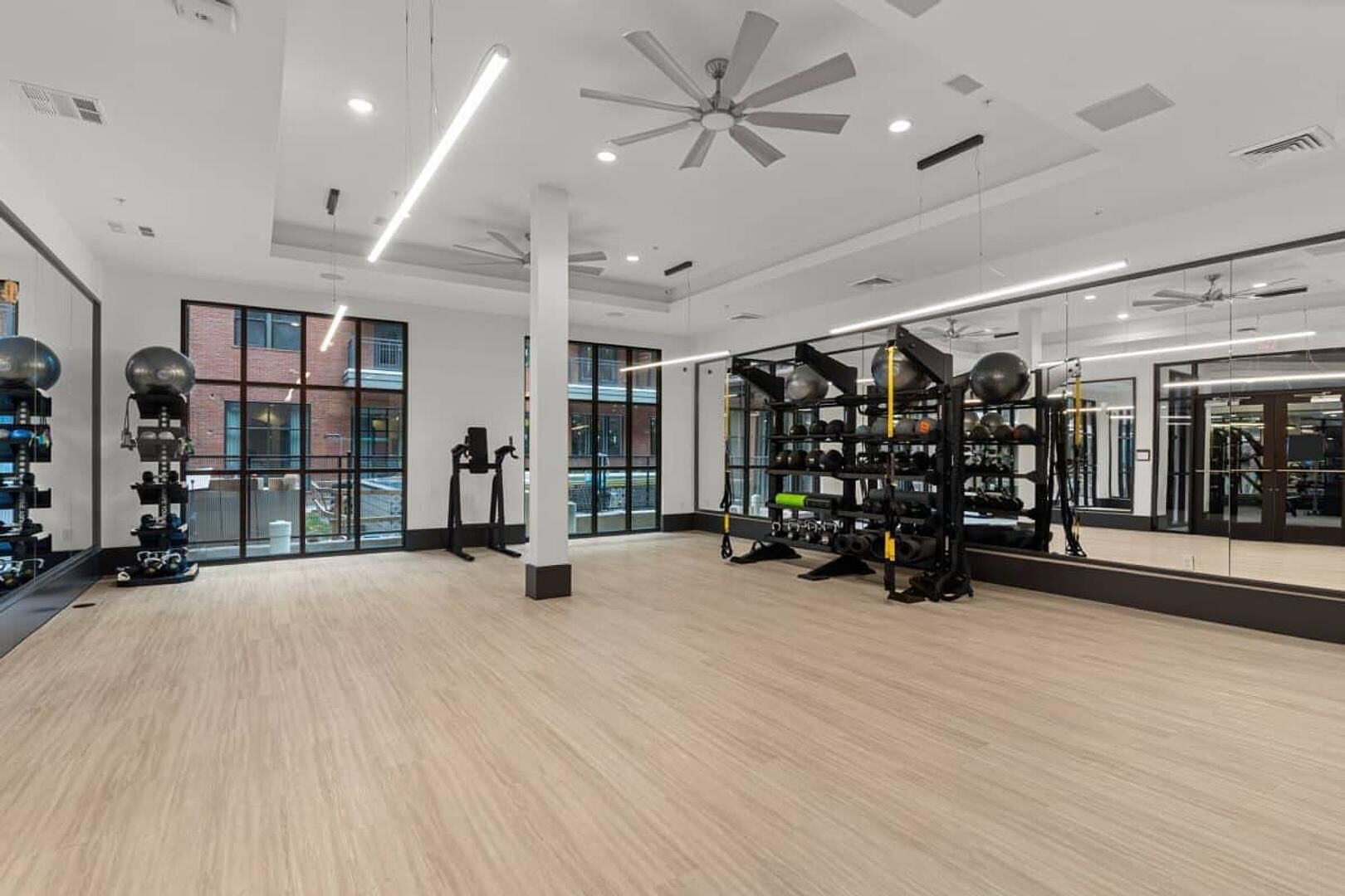 A spacious gym with exercise equipment, large windows, and a modern ceiling design.