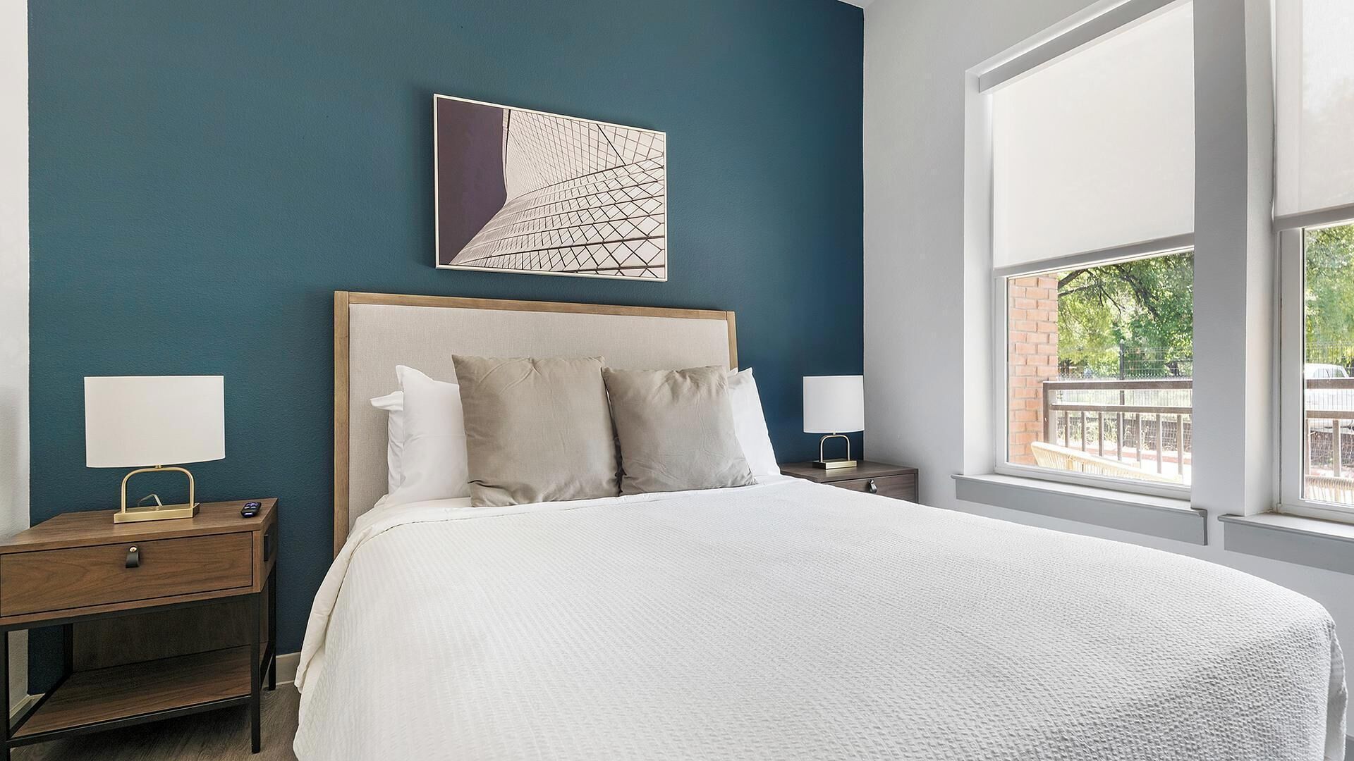 Une chambre à coucher bien aménagée, avec un grand lit, deux tables de chevet et une fenêtre donnant sur un paysage verdoyant.