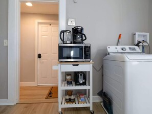 Un espace buanderie équipé d’un four à micro-ondes, d’une machine à café et d’un lave-linge, le tout installé sur un chariot.
