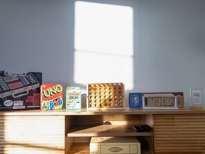 A desk with various board games and a window casting light on the surface. - Subway Harvard MIT w Parking + Yard + Outdoor (Somerville)