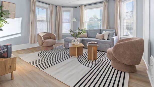 Uma sala de estar moderna com um sofá, duas poltronas, uma mesa de centro e um tapete.