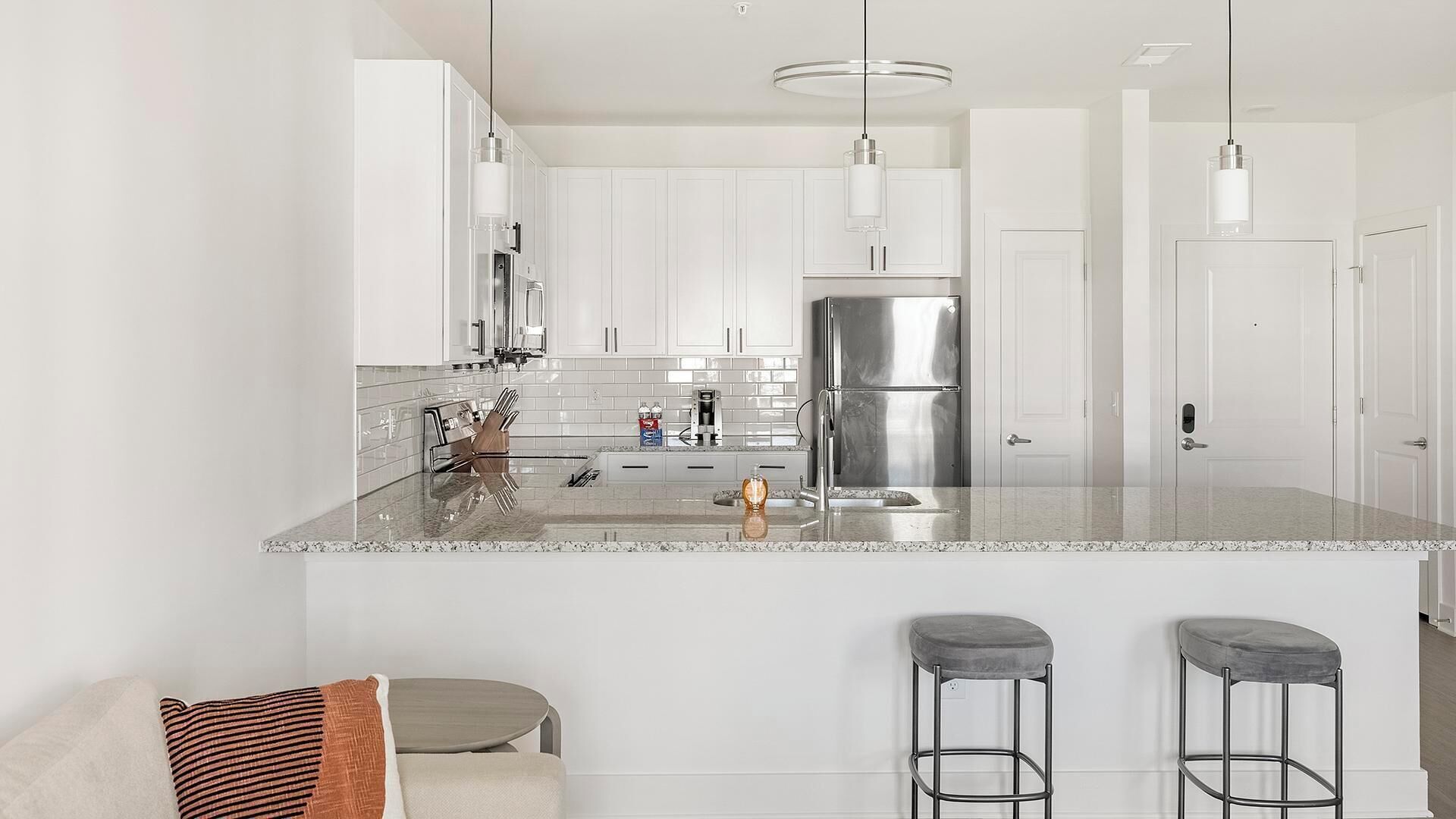 Una cocina moderna con armarios blancos, electrodomésticos de acero inoxidable y encimera de mármol.