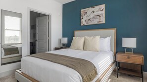 A neatly arranged bedroom with a bed, bedside tables, a nightstand, a mirror, and a painting on the wall. - Landing | Incredible 1BD, Gym, Pool (Austin)