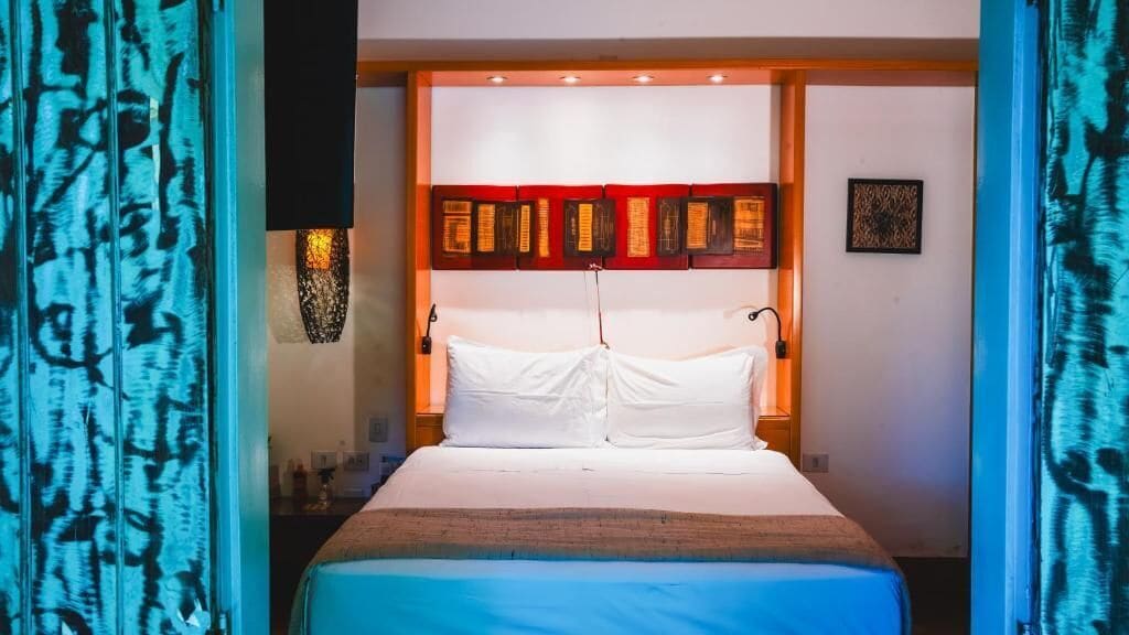 Une chambre d’hôtel avec un lit, une œuvre d’art accrochée au mur et une table de chevet.