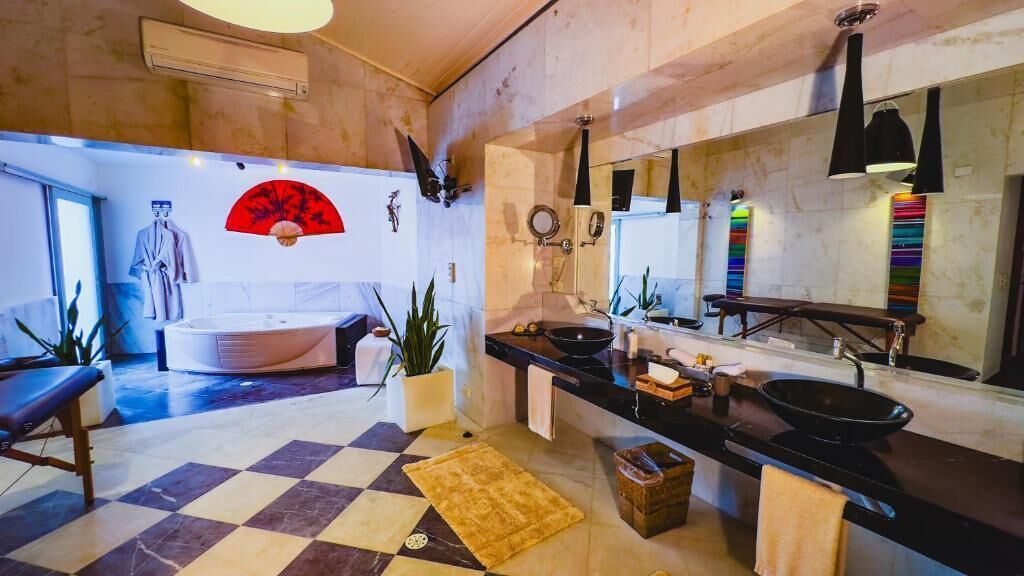 Een moderne badkamer met een badkuip, een grote spiegel en een zwart aanrecht met een wastafel.