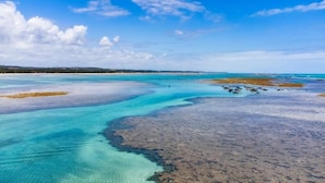 Een kustlandschap met helder turquoise water en een zandstrand.