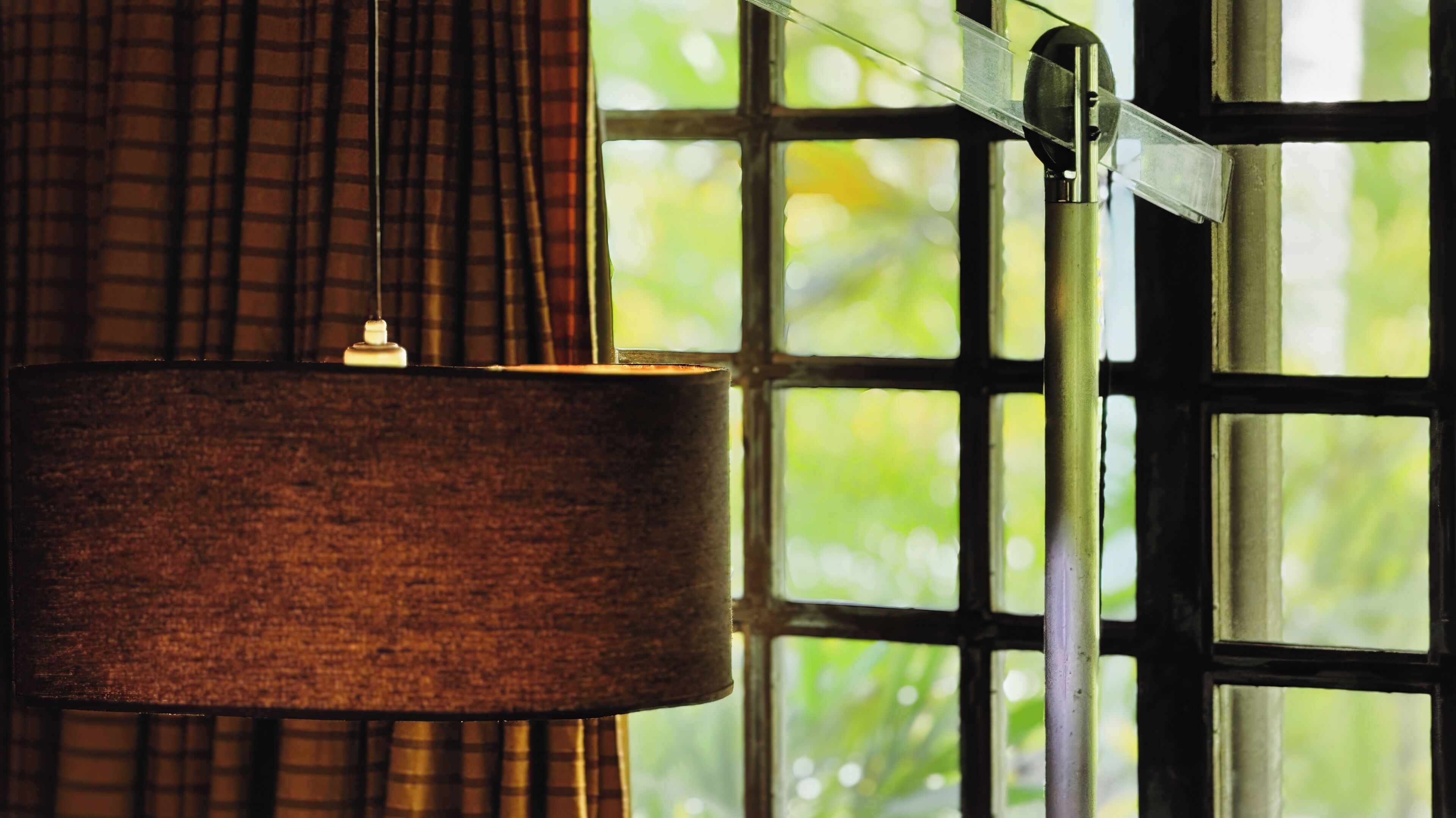 A room with a large window, a curtain, and a hanging lamp.