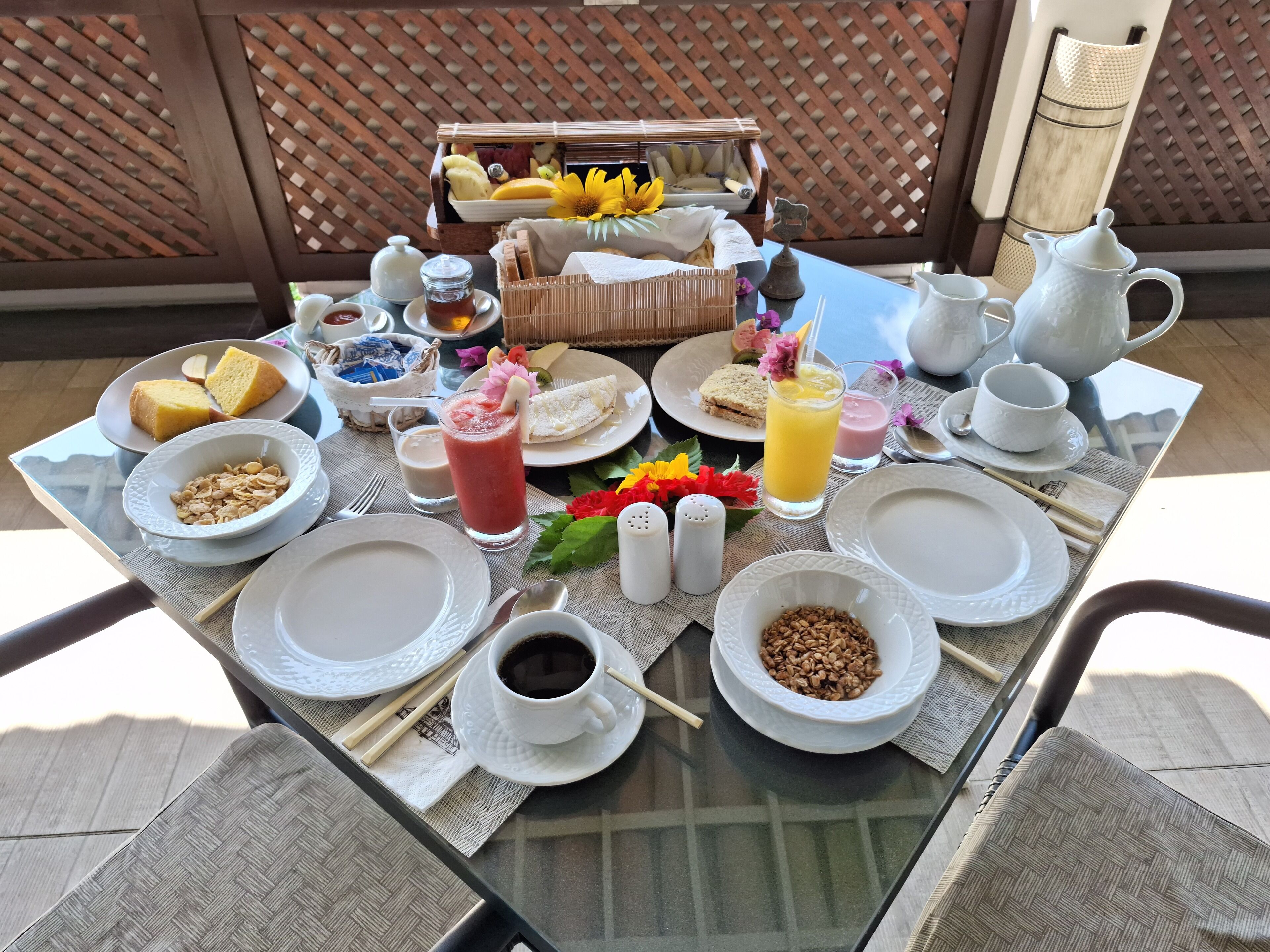 Mesa de desayuno dispuesta con platos, tazones, tazas y una jarra.