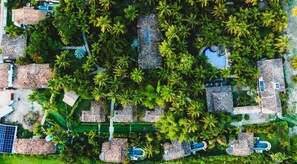 An aerial view of a resort with multiple bungalow-style accommodations surrounded by lush palm trees and a swimming pool. - CASA ACAYU (Sao Miguel dos Milagres)