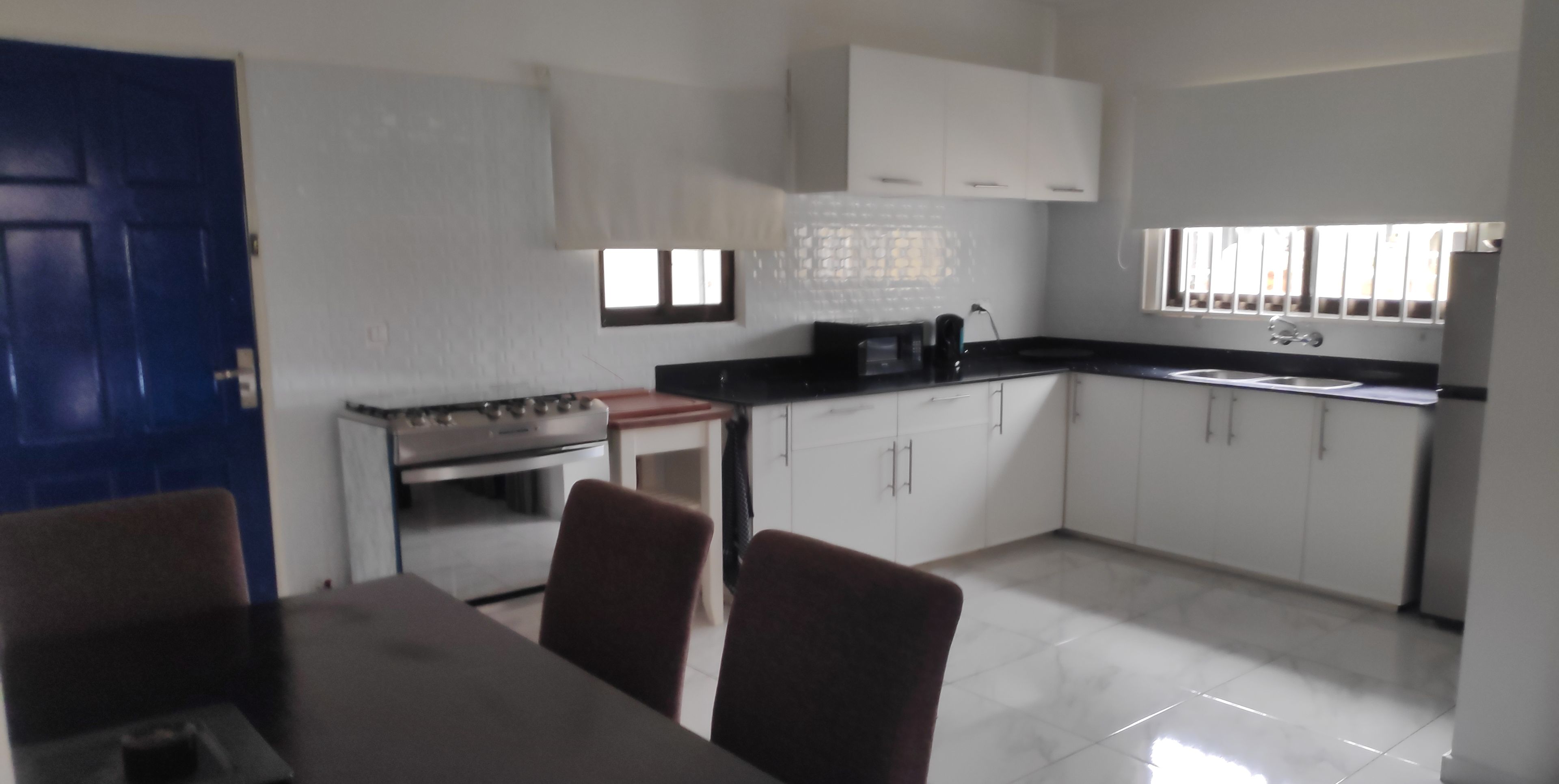A kitchen with white cabinets, a stove, and a dining table with chairs.