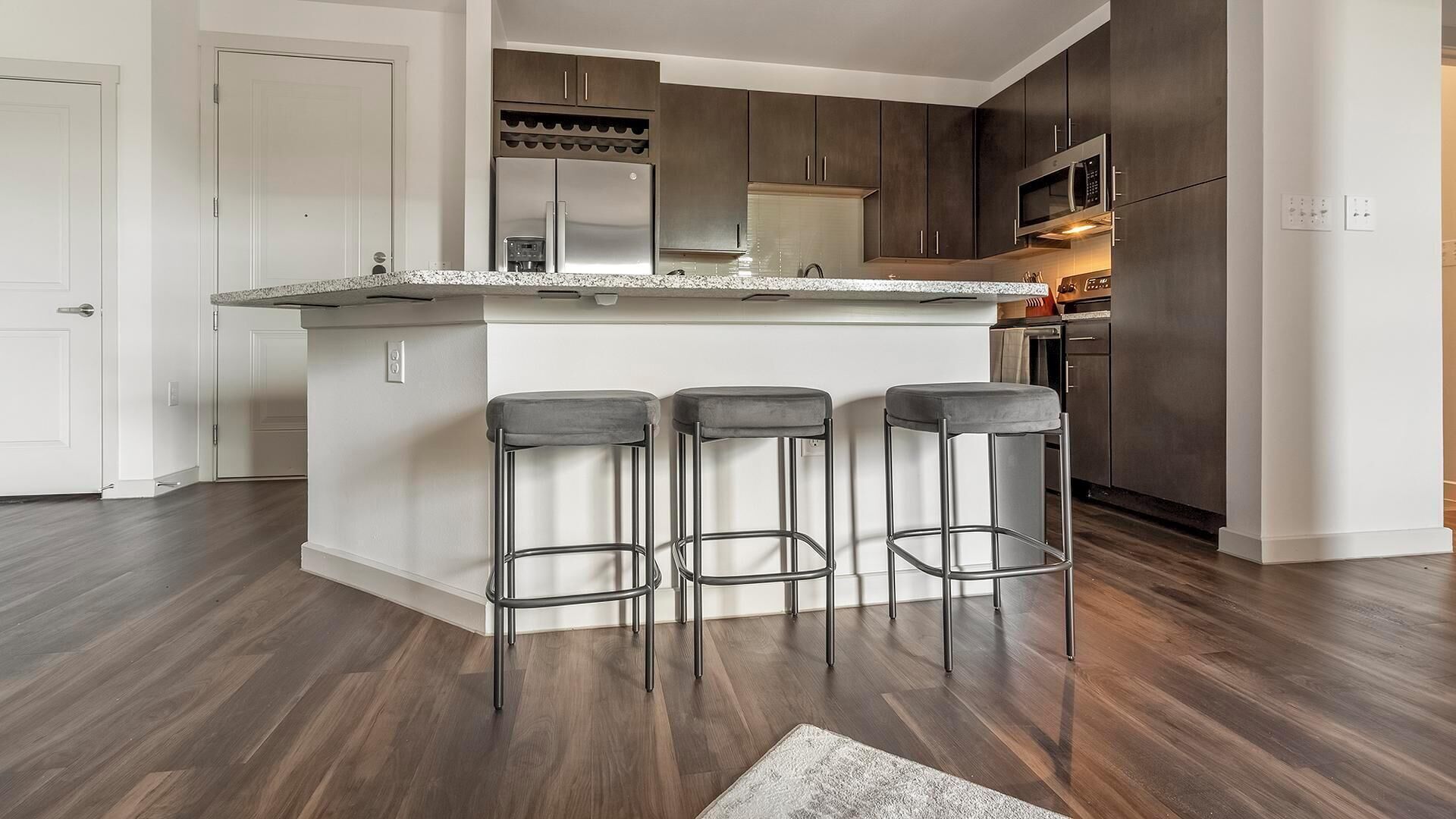A modern kitchen with a central island, stainless steel appliances, and dark wood cabinets.