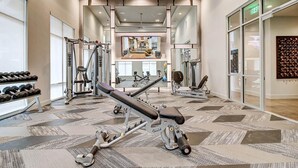 A modern gym with various exercise equipment, including dumbbells, a bench press, and cardio machines. - Landing | Beautiful 1BD, Gym, Clubhouse (San Antonio)