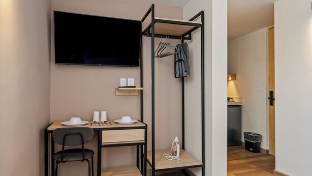 Una habitación compacta con escritorio, silla, televisión y armario empotrado con espacio para colgar.
