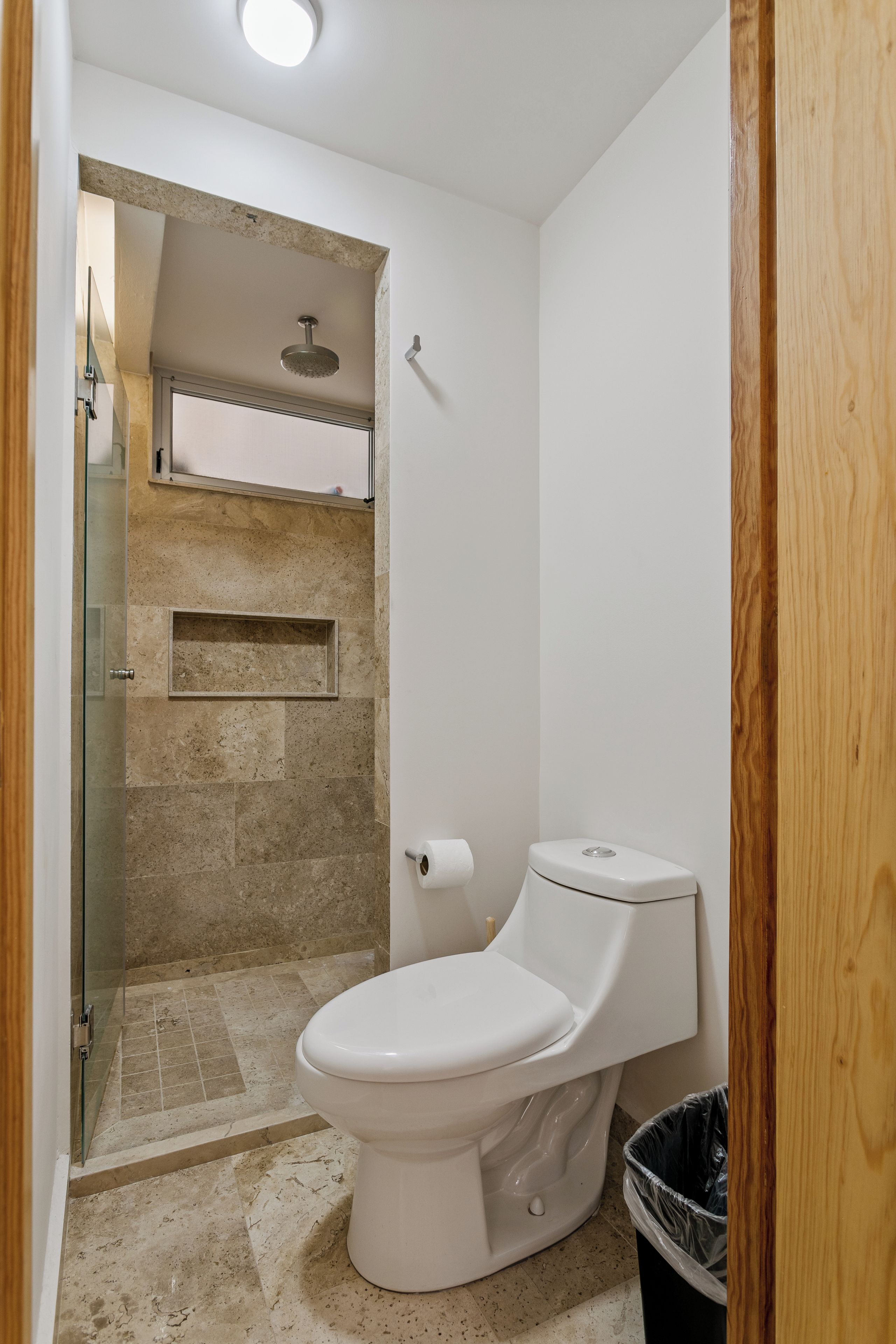 Een badkamer met toilet, douche en een glazen deur.