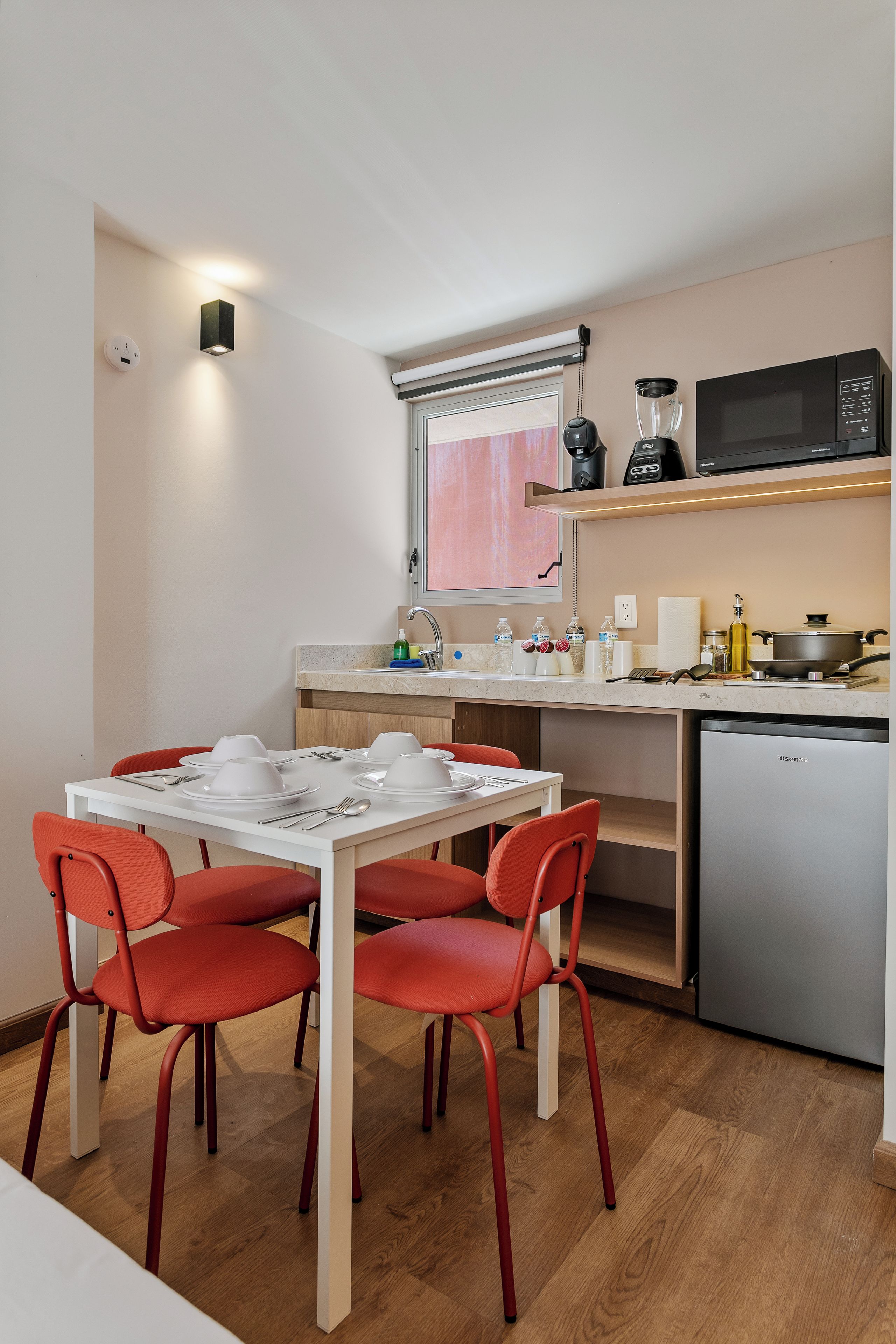 A compact kitchen with a dining table, chairs, and a refrigerator.