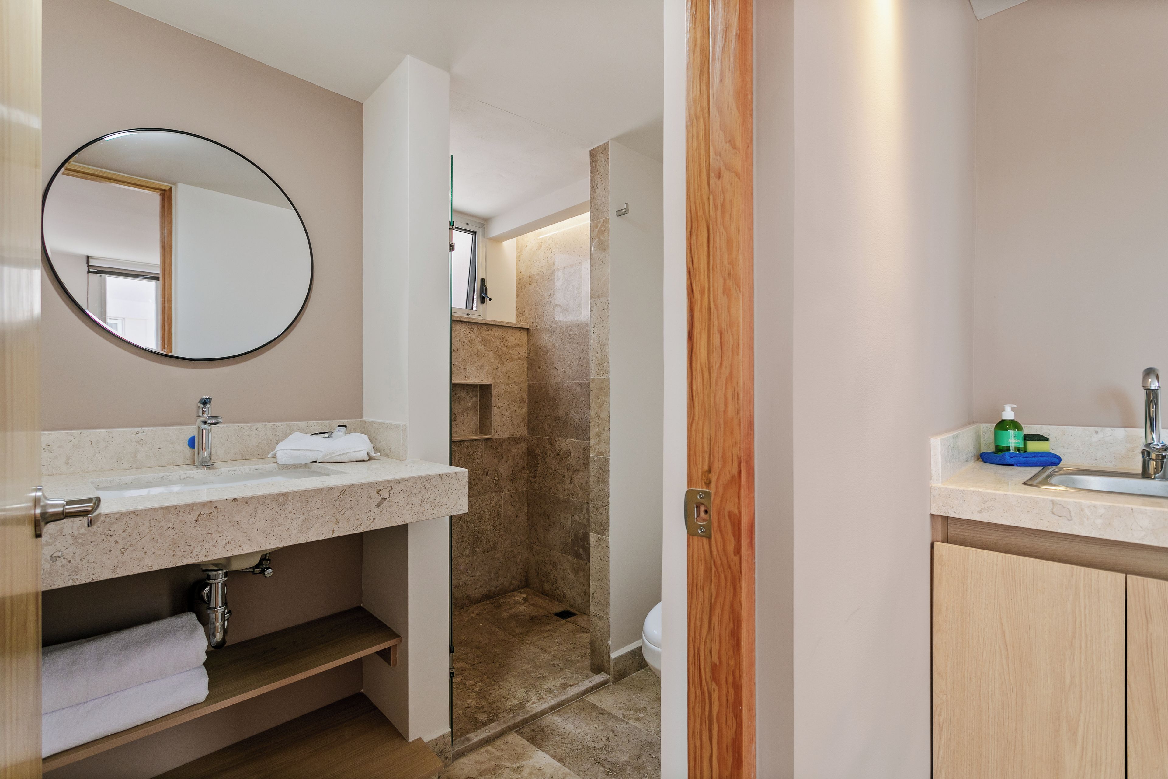 A bathroom with a sink, mirror, towel rack, and shower area.