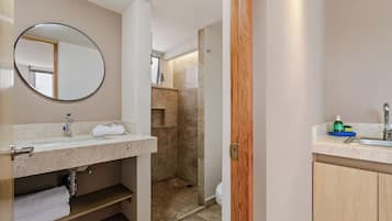A bathroom with a sink, mirror, towel rack, and shower area.