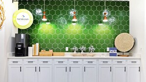 A kitchen counter with a coffee machine, a sign for Kenzie Park, and a hexagonal green backsplash. - Landing | Modern 1BD, Gym, Clubhouse (San Antonio)