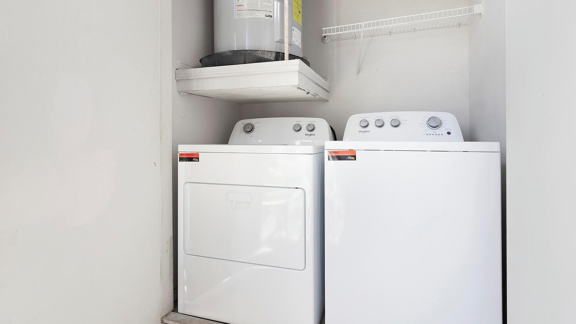 A laundry room with two white Whirlpool washers and a white dryer.