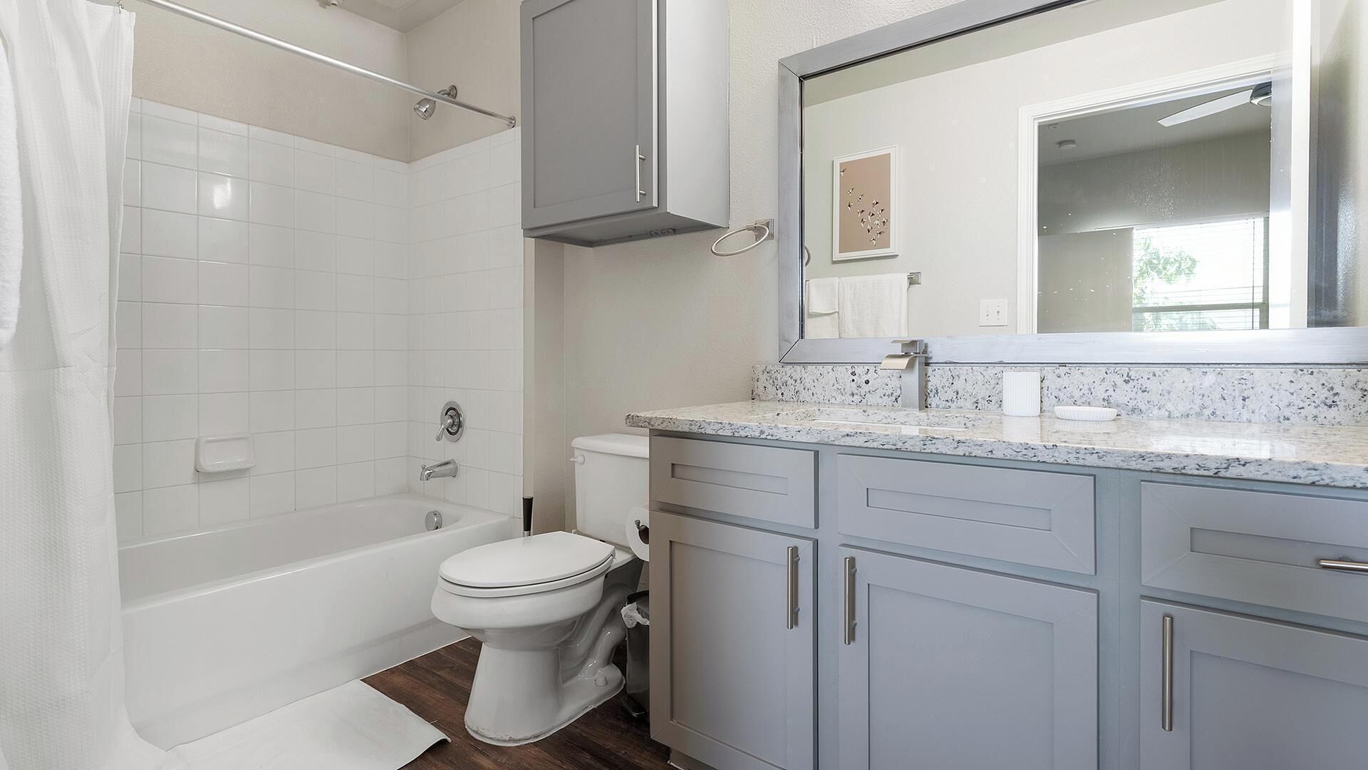 A bathroom with a bathtub, toilet, and vanity with a mirror.