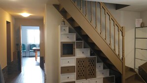 A staircase with a wooden handrail and beige steps, leading to a landing with a white storage unit with multiple drawers and a mirrored wall. - Villa with private heated pool in Normandy (Treis-Sants-en-Ouche)