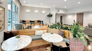 Un área de estar moderna con asientos, mesas y plantas en macetas.