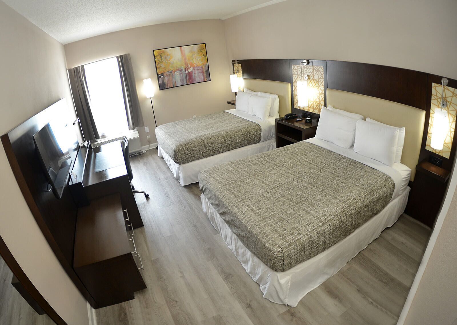 Ein Hotelzimmer mit zwei Betten, einem Schreibtisch, einem Stuhl und einem Fernseher.
