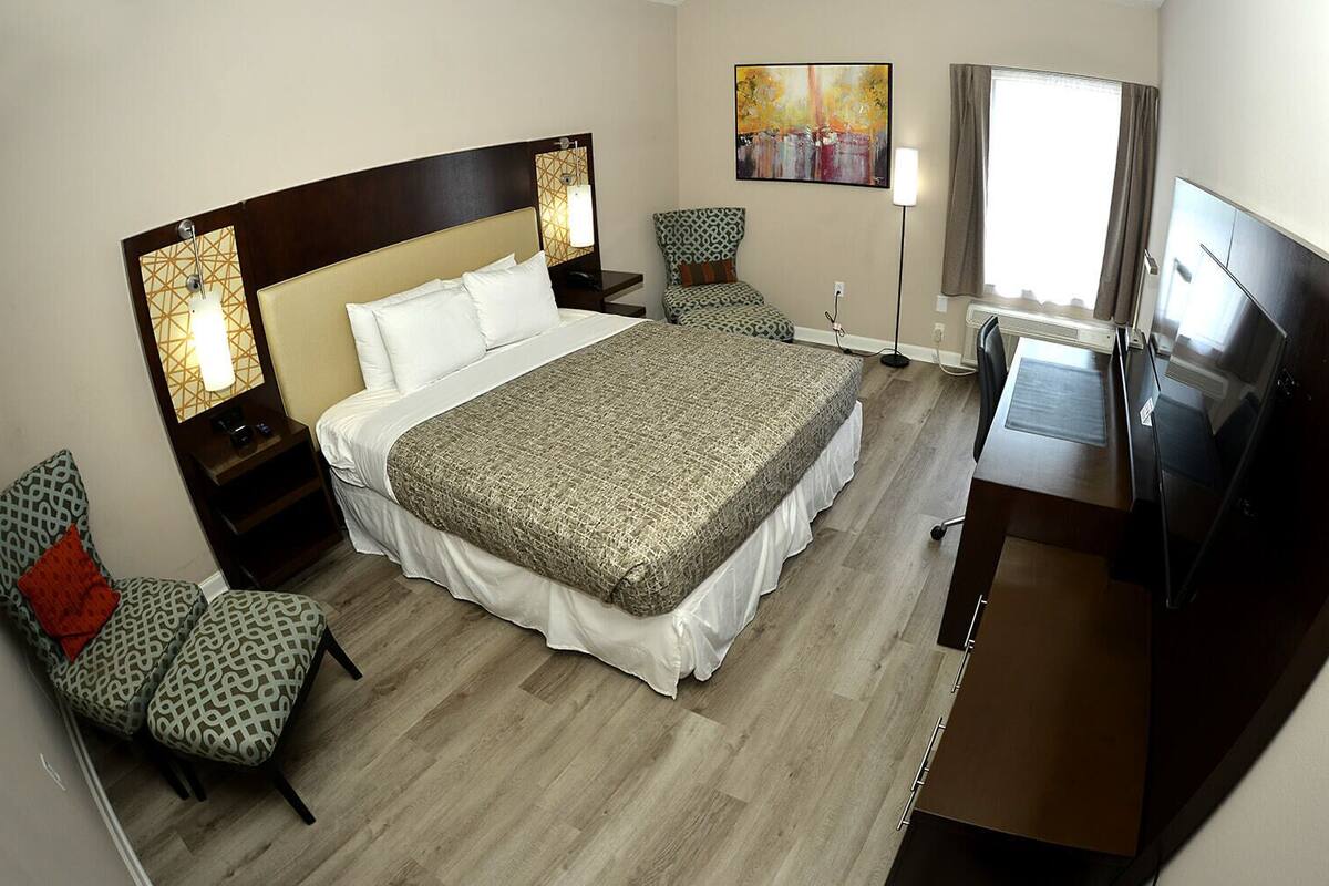 Une chambre d’hôtel avec un grand lit, un bureau, une chaise, une télévision et un tableau au mur.