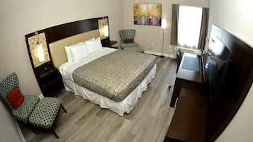 Una habitación de hotel con una cama grande, un escritorio, una silla, un televisor y un cuadro en la pared.