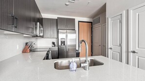 A modern kitchen with stainless steel appliances, a granite countertop, and a double sink. - Landing | Beautiful 1BD, Gym, Clubhouse (San Antonio)