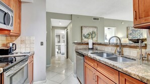 Una cocina moderna con encimeras de granito, electrodomésticos de acero inoxidable y armarios de madera.