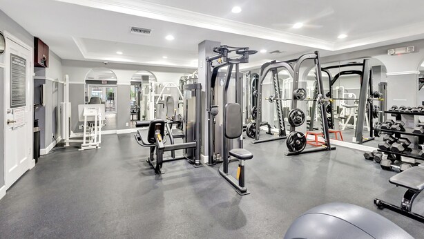 Un gimnasio con diverso equipamiento de ejercicio, que incluye máquinas de pesas y mancuernas.