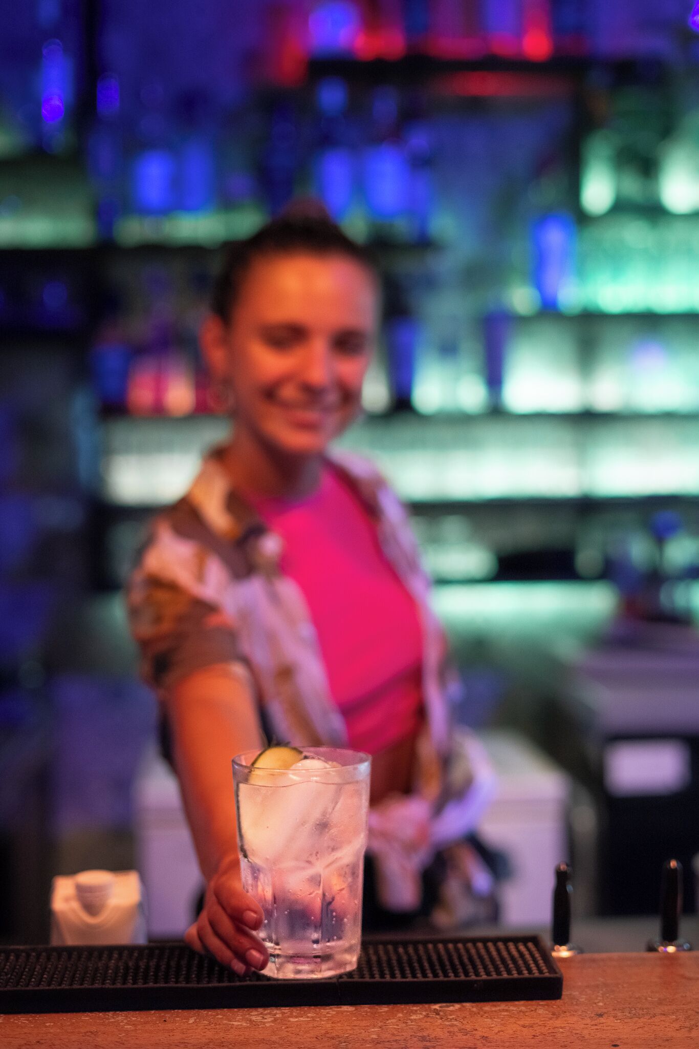 A bar setting with a person holding a glass of water with a lemon slice.