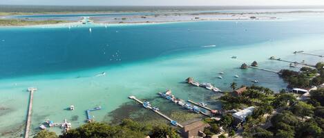 An aerial view of a coastal area with clear turquoise waters, boats, and docks.