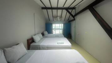 A room with two beds, a ceiling fan, and a window with curtains.