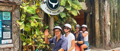A group of people on a scooter in front of a rustic building with a sign that reads "LAKE HOUSE."