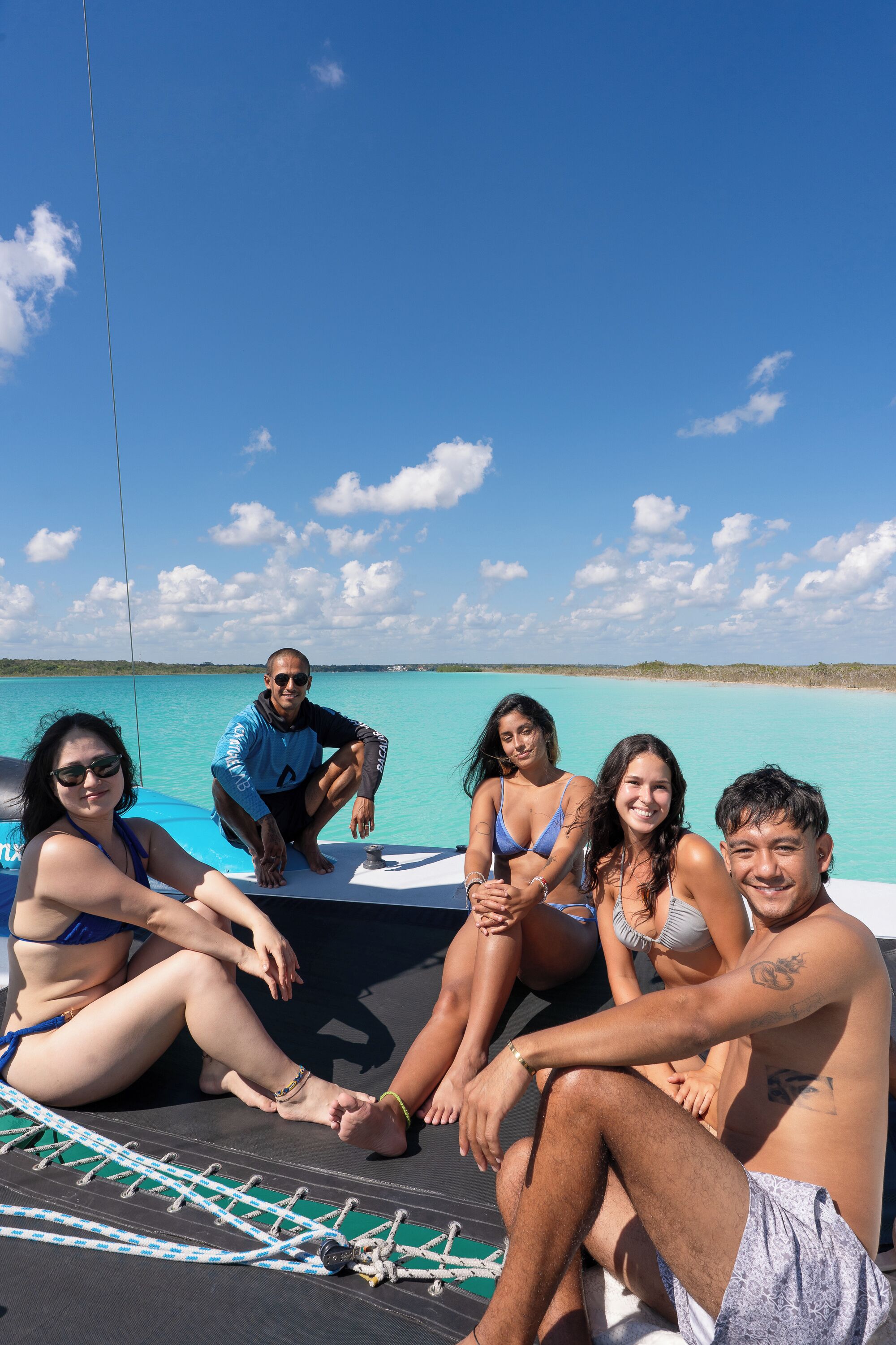 A group of people on a boat with a clear blue sky and calm sea in the background.