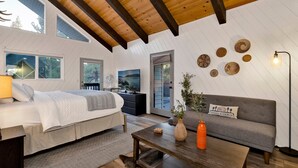 A cozy bedroom with a bed, a dresser, and a nightstand. There is a gray sofa and a coffee table with a vase and a lamp. - Balboa at Big Bear #404 (Big Bear Lake)
